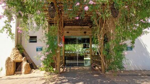 A wooden pergola with climbing plants and a glass door entrance. - Pousada Faruk (Olímpia)