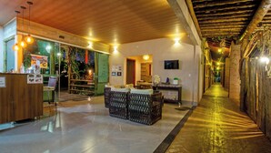 A hotel lobby with a reception desk, seating area, and a corridor leading to other rooms. - Pousada Faruk (Olímpia)