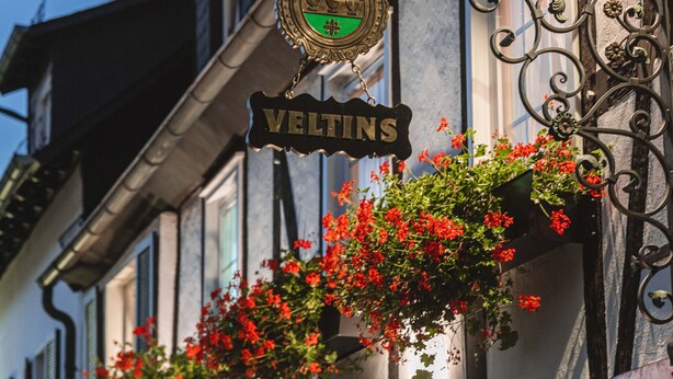 Un bâtiment sur lequel on peut lire l’inscription « VELTINS », avec un emblème décoratif au-dessus.