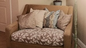 A brown sofa with patterned cushions and a tall floor lamp beside it. - La Maison de Textile (Montolieu)