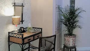 A small room with a desk, chair, potted plant, and a wall-mounted lamp. - La Maison de Textile (Montolieu)