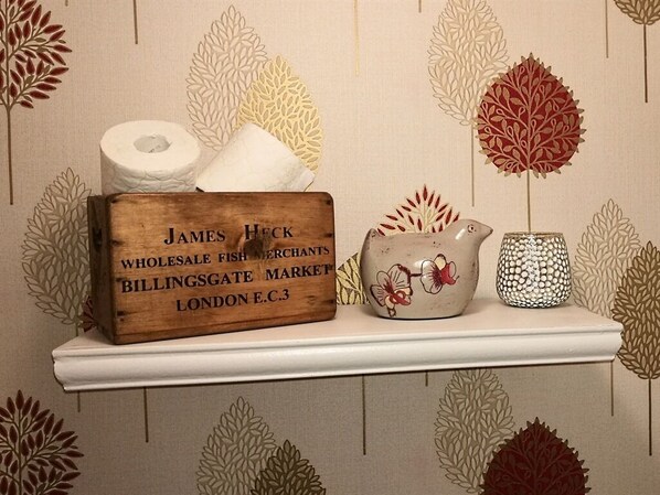 A shelf with a wooden box labeled 'James Heck Wholesale Fish Merchants Billingsgate Market London E.C.3', a roll of toilet paper, and two ceramic items. - La Maison de Textile (Montolieu)