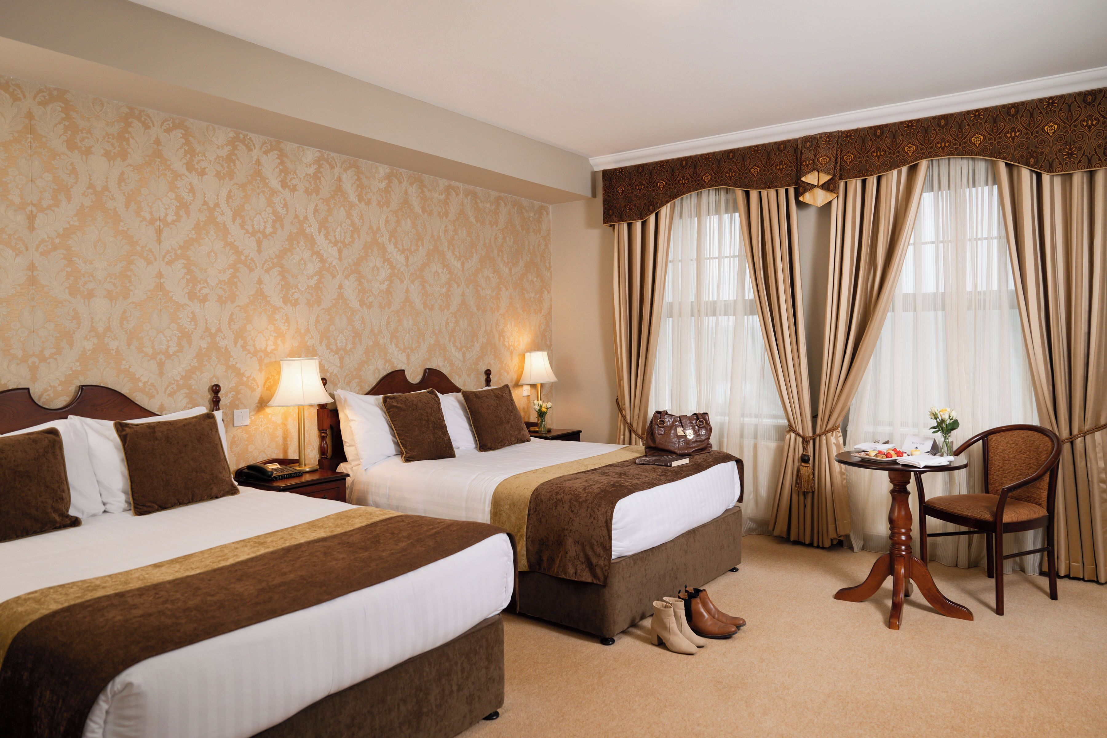 Une chambre d’hôtel avec deux lits, une petite table avec une chaise et un mur décoratif.