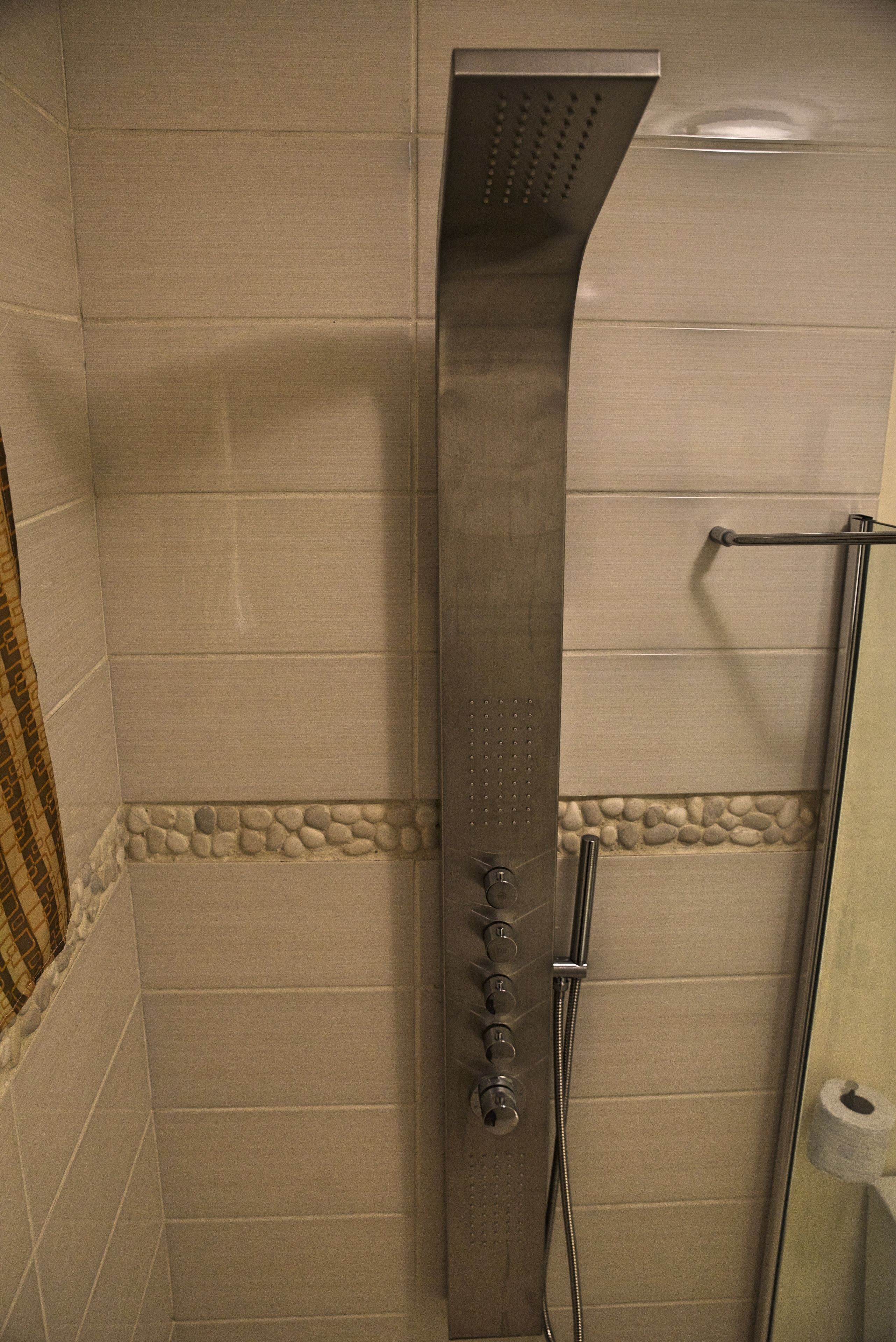 Une douche équipée d’un panneau de commande et d’une barre d’appui.