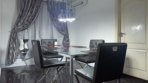 A conference room with a glass table, black chairs, a chandelier, and grey curtains. - GGC Apartments (Lagos)