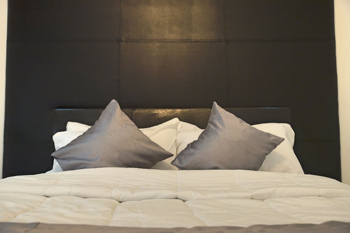 A bed with a dark headboard and two pillows.