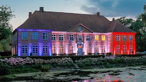 Un grand bâtiment en briques, doté de nombreuses fenêtres et d’une entrée centrale.