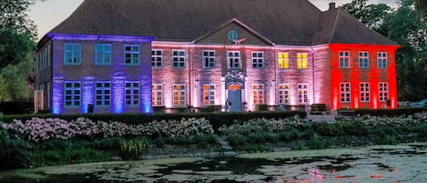 Un grand bâtiment en briques, doté de nombreuses fenêtres et d’une entrée centrale.