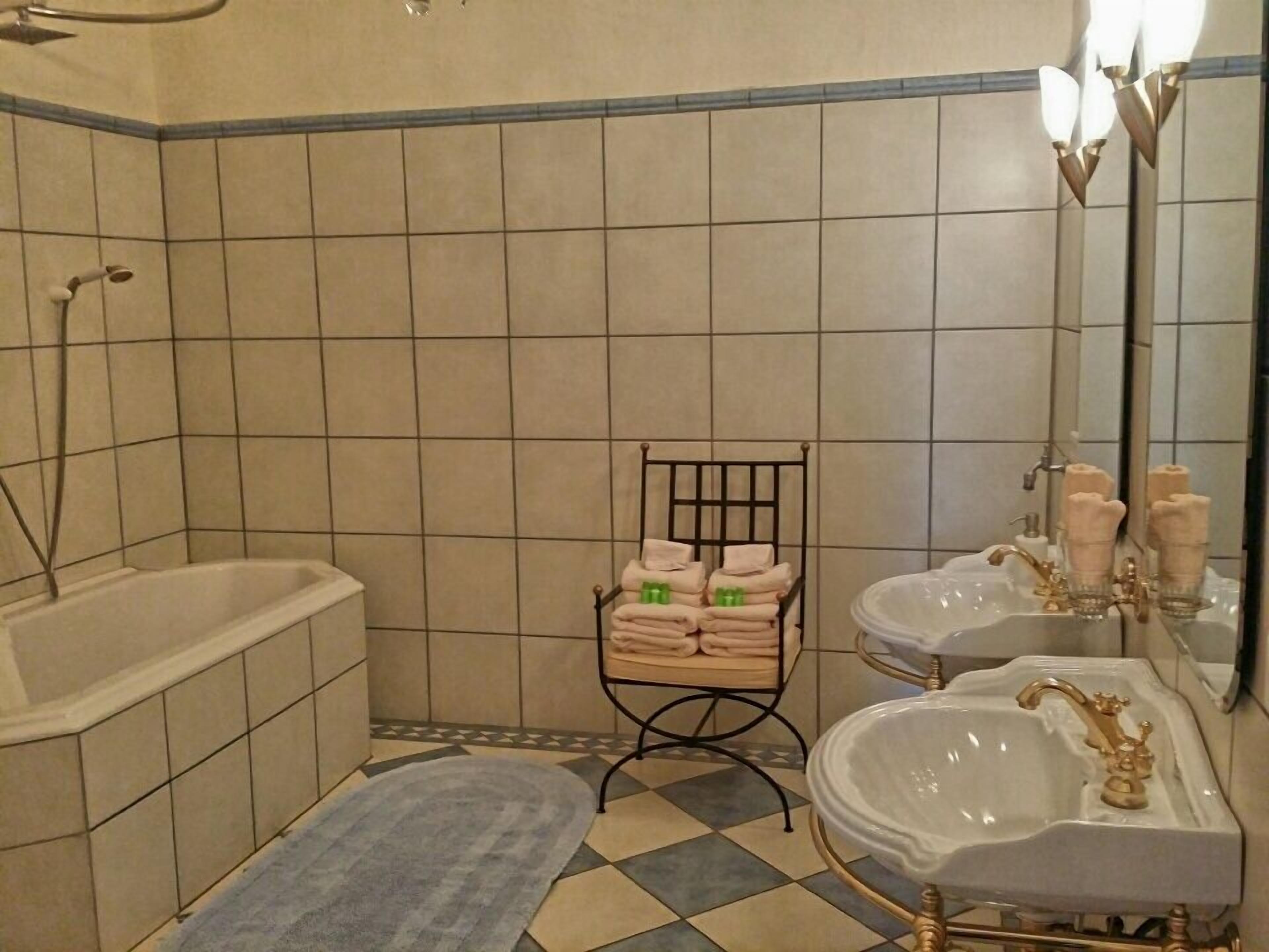 Un baño con bañera, dos lavamanos, un espejo y un perchero para toallas.
