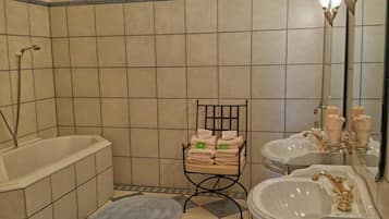 Un baño con bañera, dos lavamanos, un espejo y un perchero para toallas.
