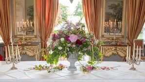 Une table à manger élégante, agrémentée d’un centre de table floral, de bougeoirs et d’une nappe blanche.