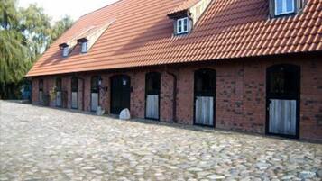A brick building with a tiled roof, multiple windows, and a cobblestone driveway.