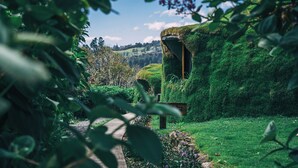 A traditional thatched-roof house surrounded by lush greenery and a clear sky. - Bambuda Castle - Hostel (Los Naranjos)