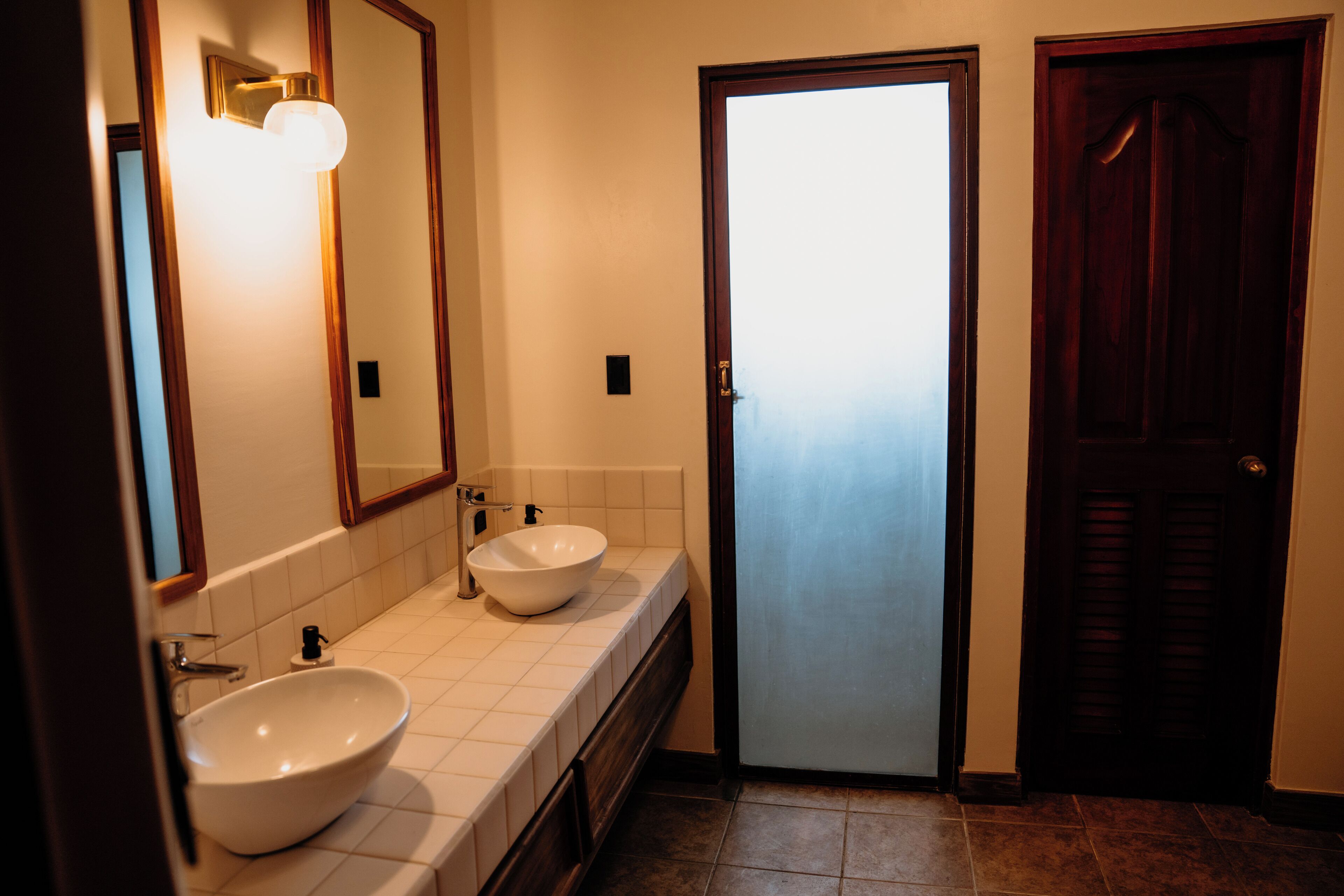 Un baño con dos lavabos, un espejo y una puerta.
