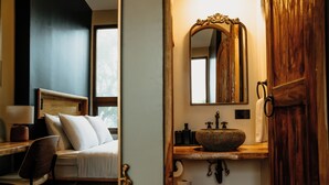 A modern bathroom with a wooden vanity, a large mirror, and a stone sink. - Bambuda Castle - Hostel (Los Naranjos)