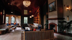 A cozy, well-lit interior with a wooden ceiling, a fireplace, and a seating area with a sofa and chairs. - Bambuda Castle - Hostel (Los Naranjos)