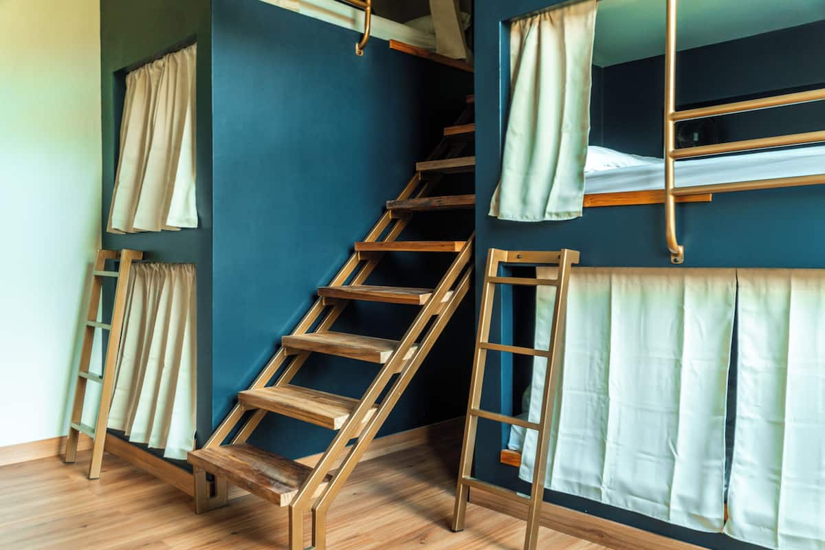 A room with bunk beds, wooden ladders, and curtains.
