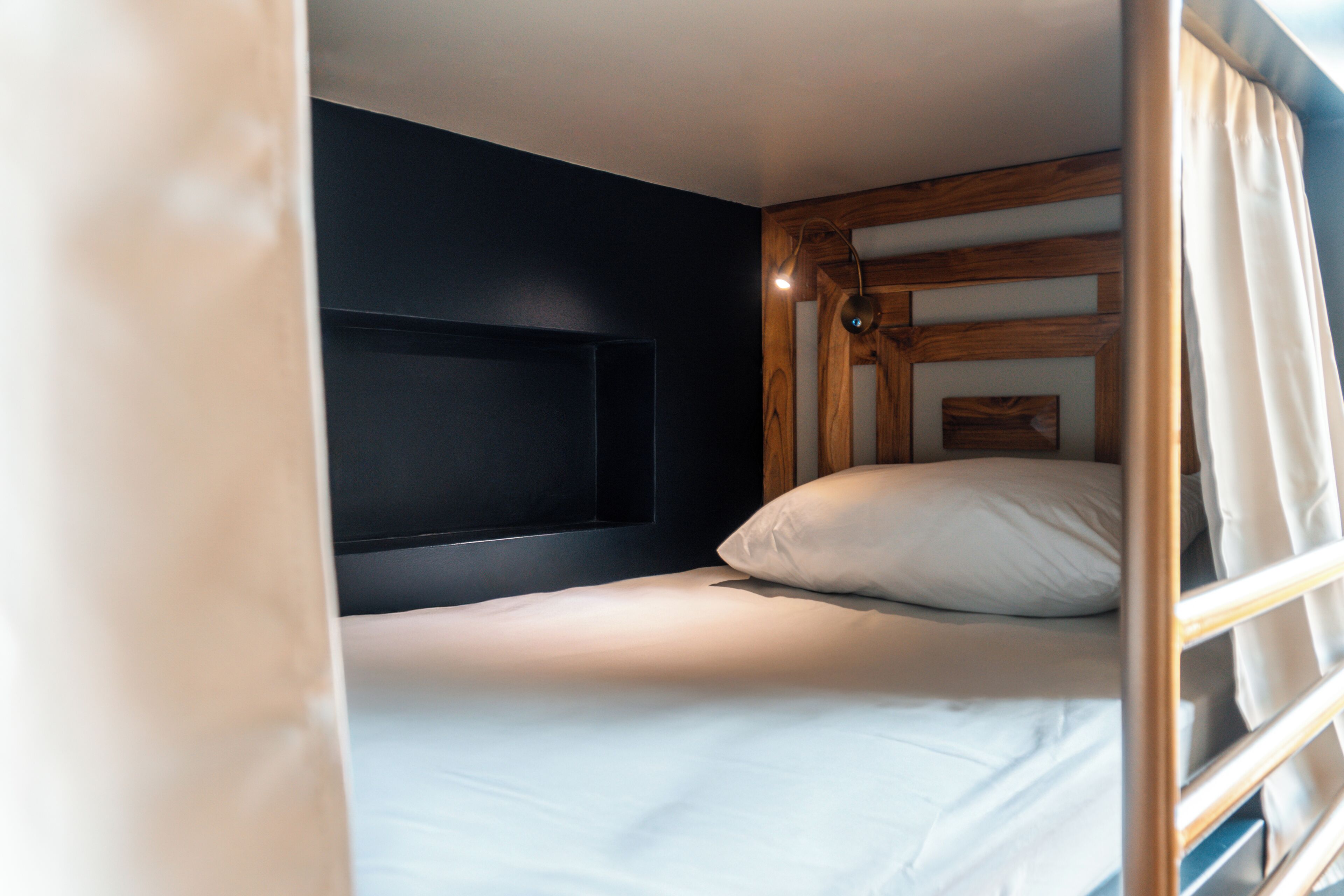 A bunk bed with a headboard, a bedside table, and a lamp.