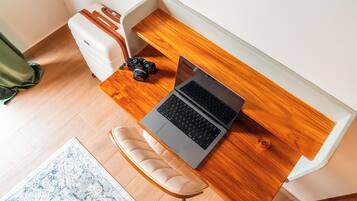 A compact workspace with a laptop, camera, and a cushioned bench.