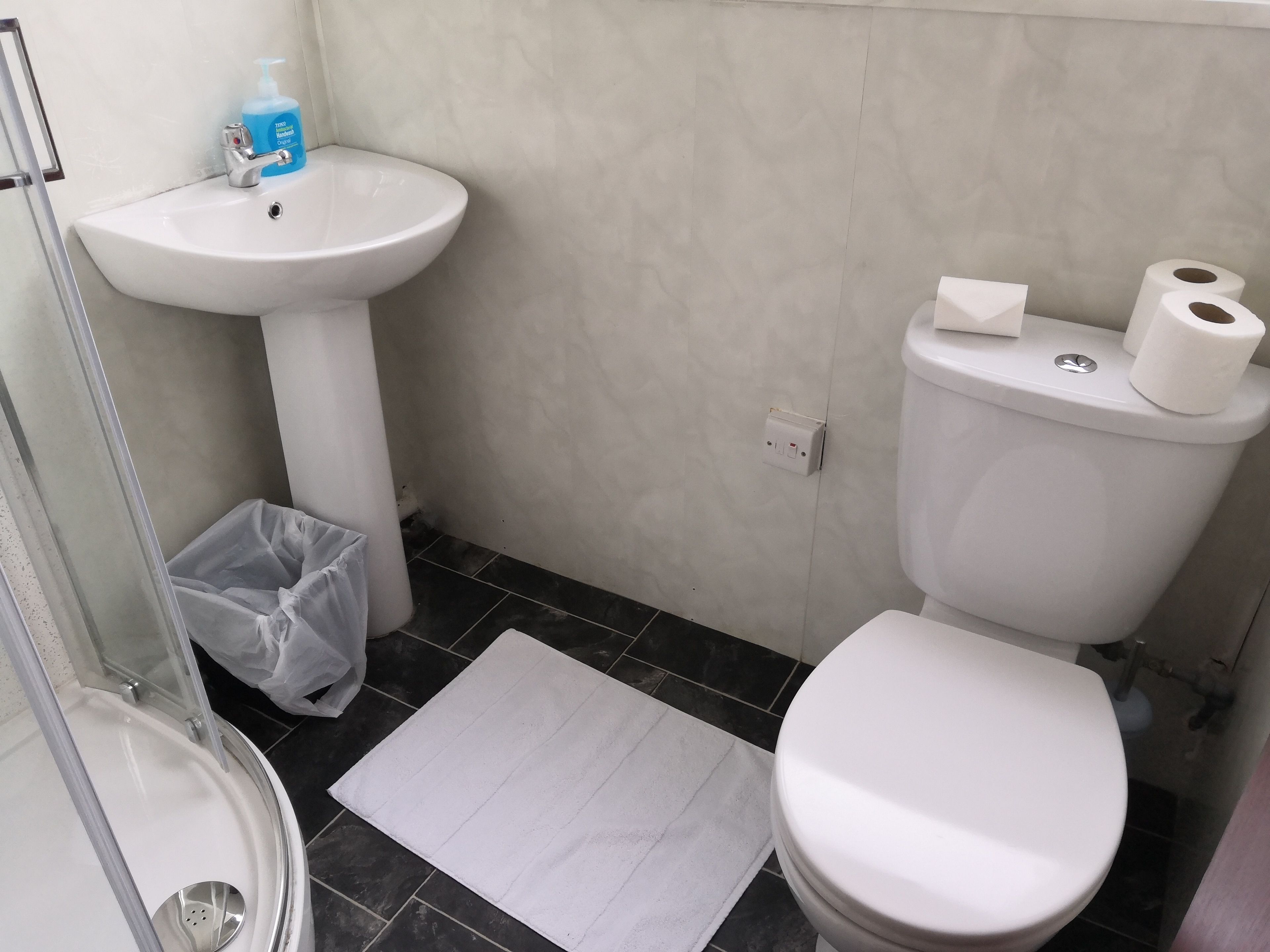 Un baño con lavamanos, inodoro y ducha blancos.