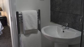 A bathroom with a white sink, a towel rack, and a trash bin.