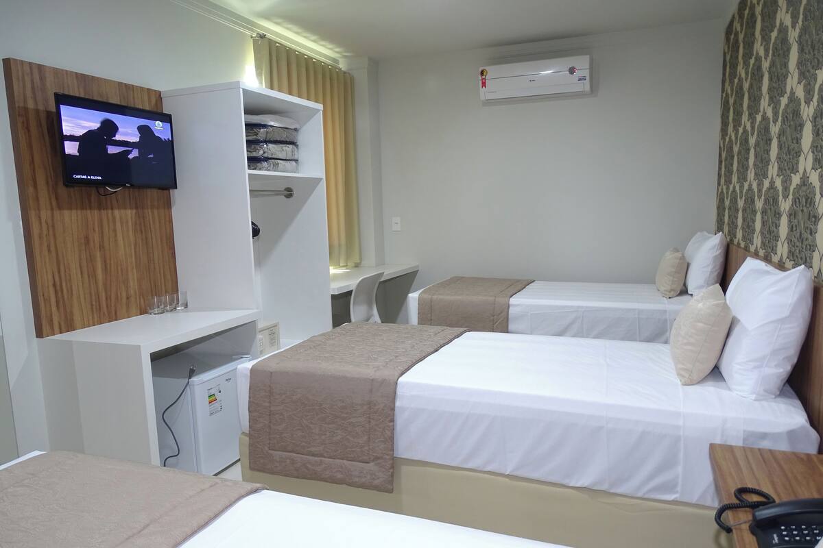 A hotel room with two beds, a TV, a wardrobe, and a desk.