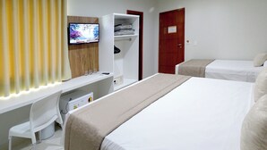 Habitación de hotel con cama, escritorio con computadora, televisor, armario y puerta.