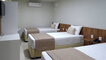 Habitación de hotel con tres camas, un escritorio y un teléfono.