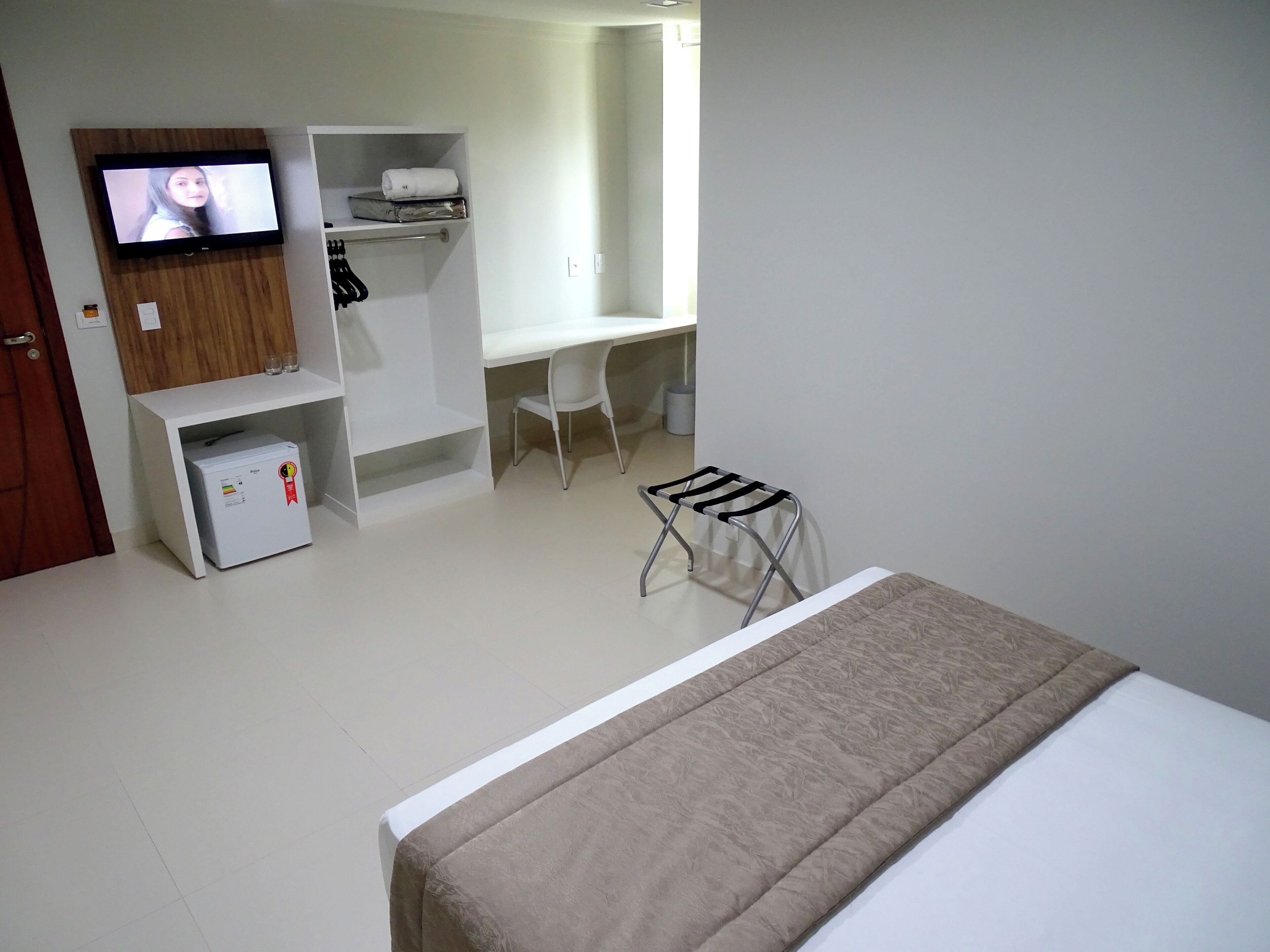 Un dormitorio con cama, escritorio, silla, televisor y armario.