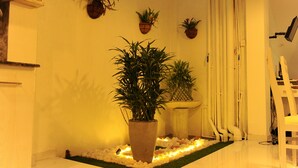 A corner of a room with a first aid box, potted plants, and a white chair. - Fort Heaven (Galle)
