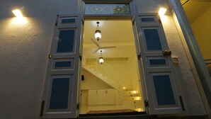 A hotel entrance with a staircase leading to the upper floor, a fan, and a light fixture above the door. - Fort Heaven (Galle)