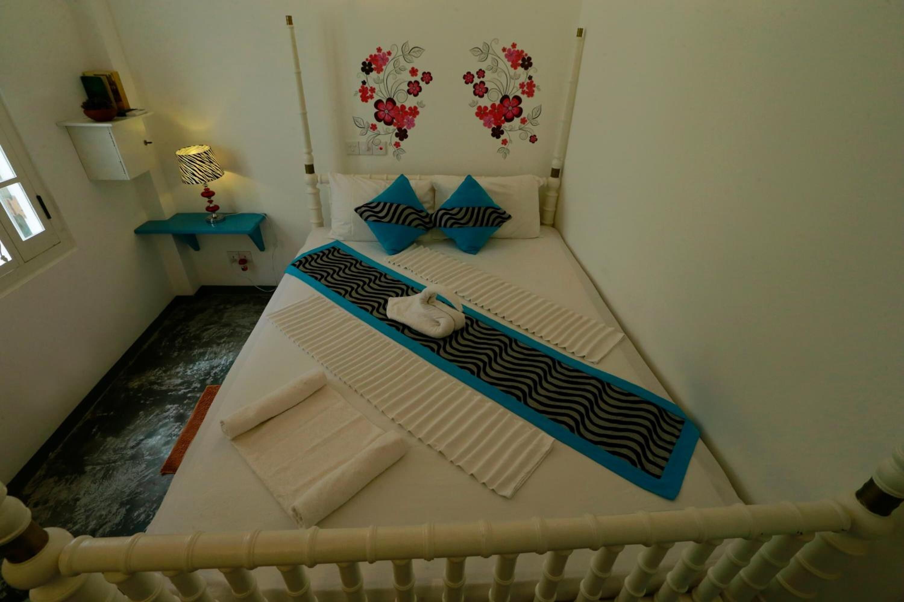 A neatly arranged bedroom with a bed, pillows, a bedside table, and a wall decoration.