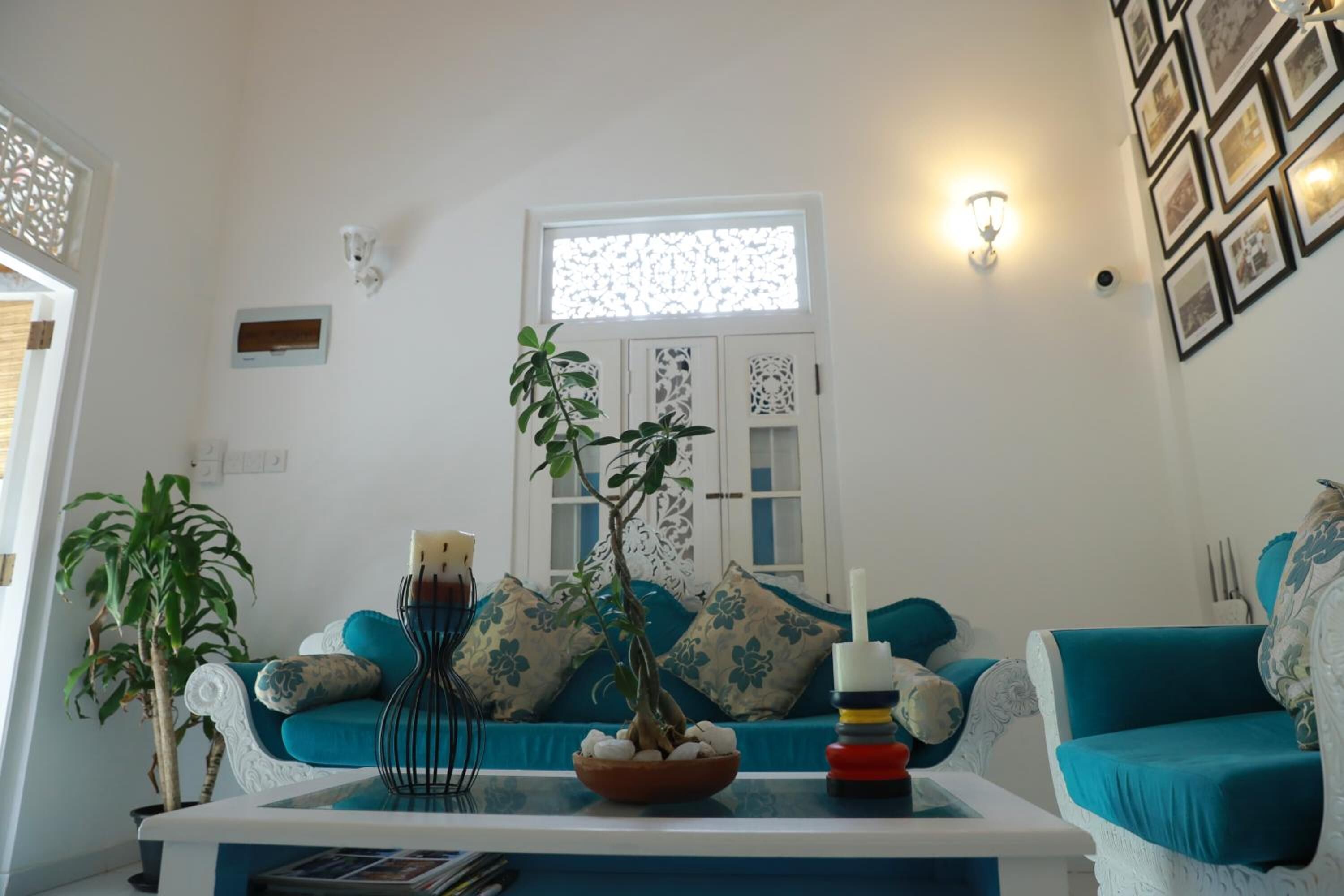 A living room with a sofa set, a coffee table with a plant, and a decorative wall.