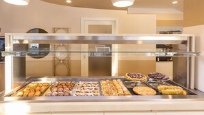 Mostrador de pastelería con diversos productos de repostería y una puerta de cristal.