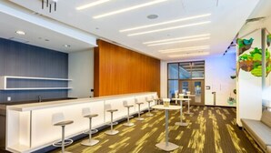Una hall moderna di un hotel, con reception, posti a sedere al bar e un tappeto decorato.