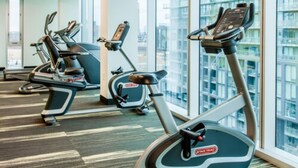 Palestra con macchinari cardio e ampie finestre che offrono vista sulla città.
