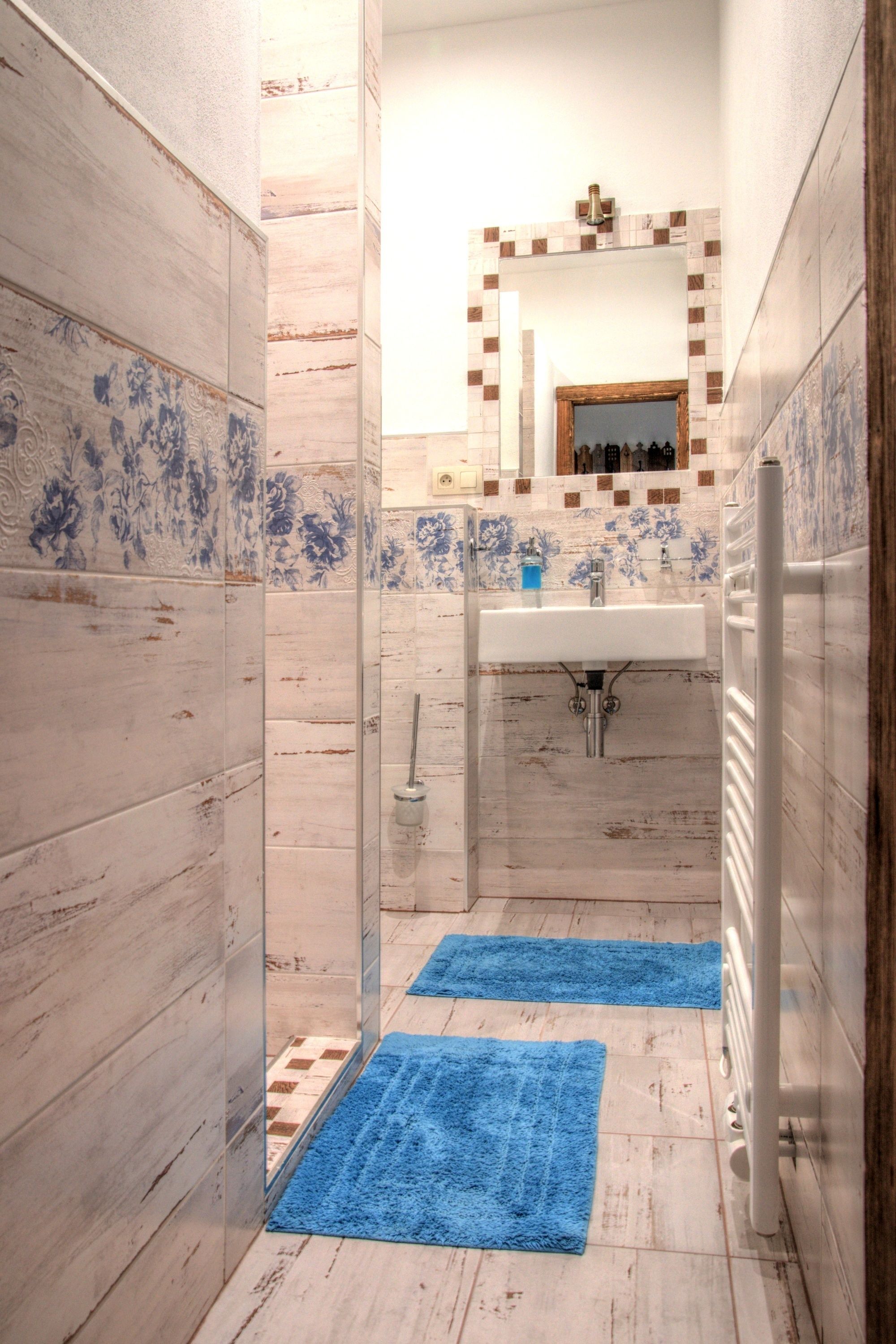 Une petite salle de bain avec un lavabo, un miroir et des serviettes bleues sur le sol.