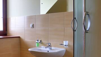 Une salle de bain avec un lavabo, un miroir et une porte de douche en verre.