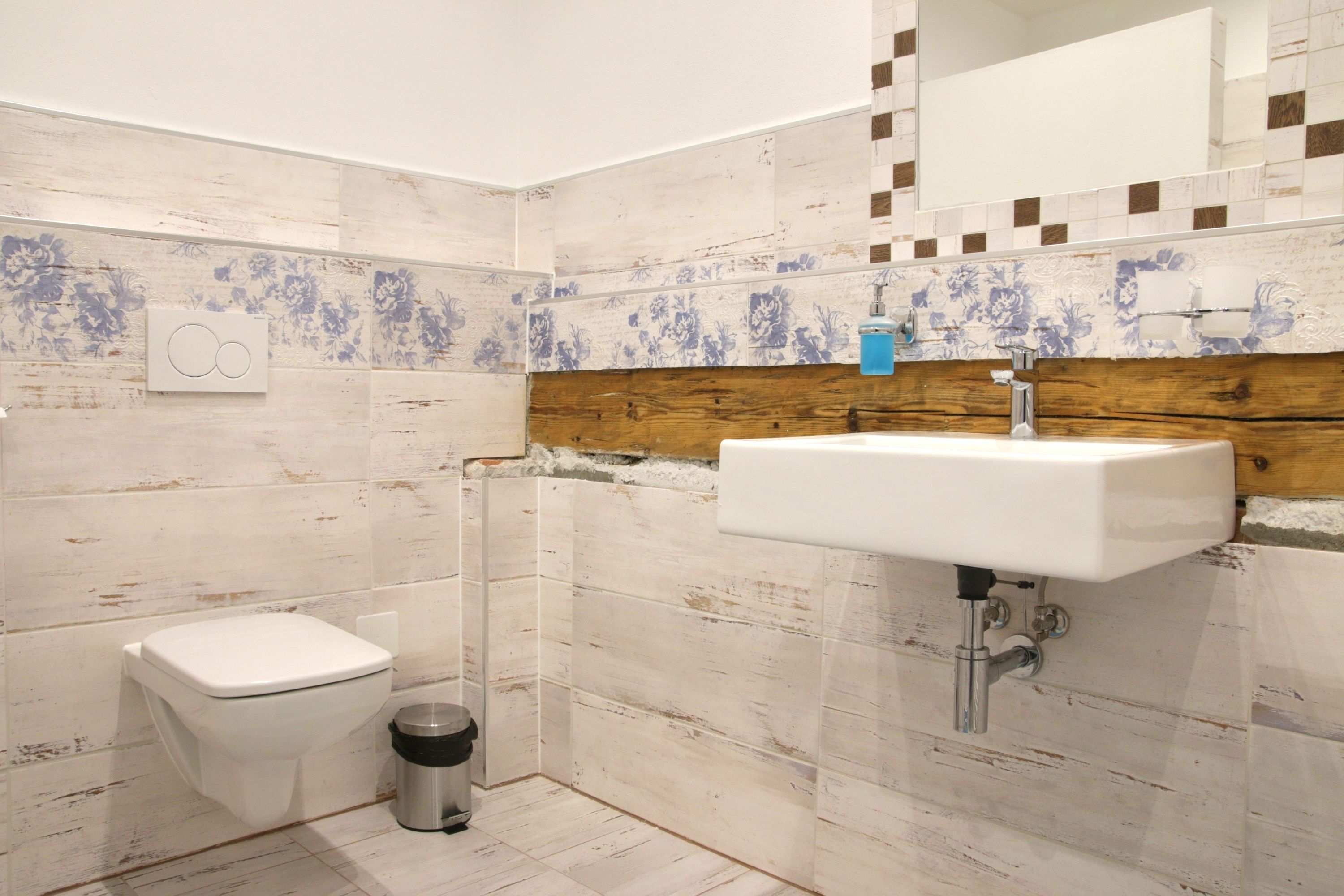 A bathroom with a toilet, a sink, and a trash can.