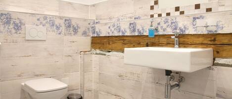 Un baño con inodoro, lavamanos y cubo de basura.