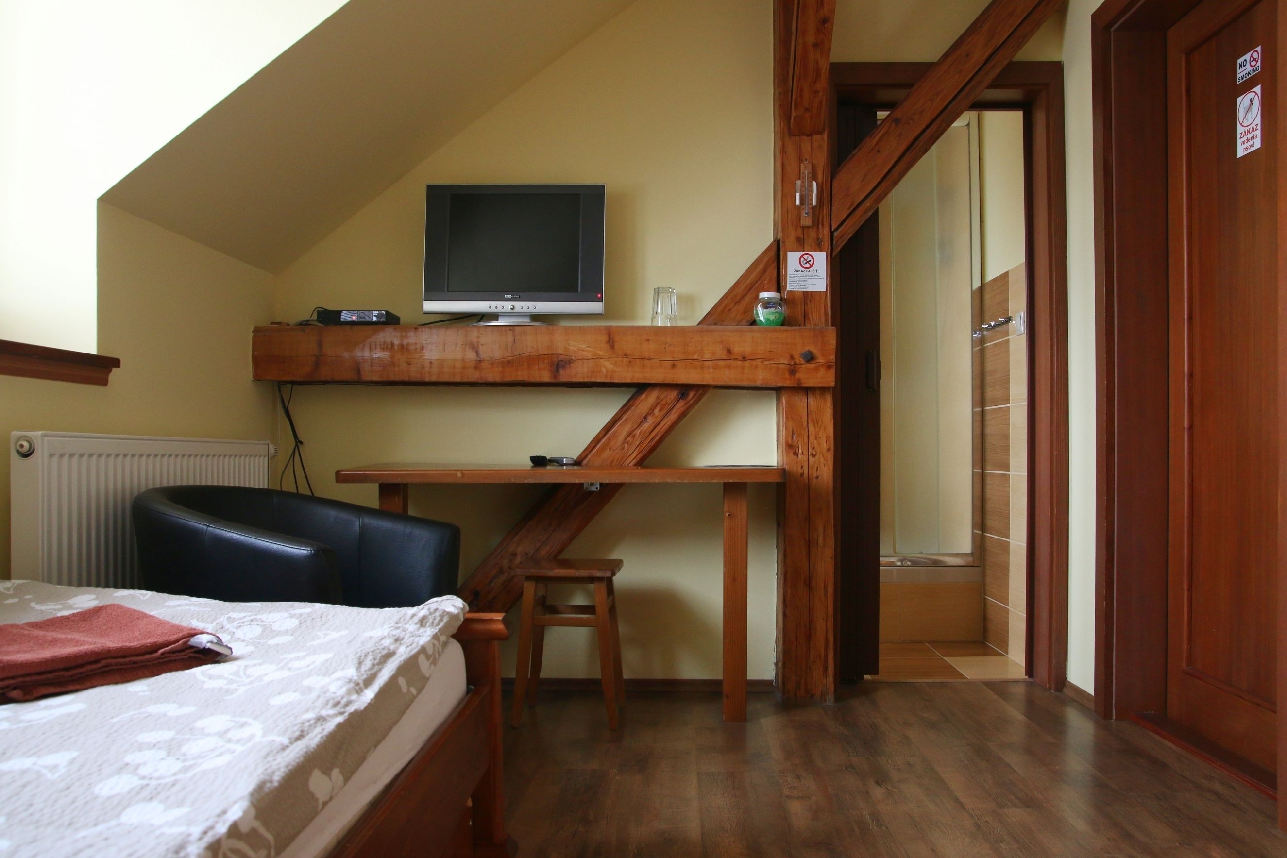 A bedroom with a bed, a desk, a chair, a television, and a bathroom door.