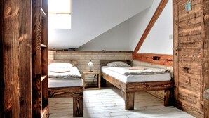 Un dormitorio tipo loft con dos camas de madera, una pared de ladrillo y un techo inclinado.