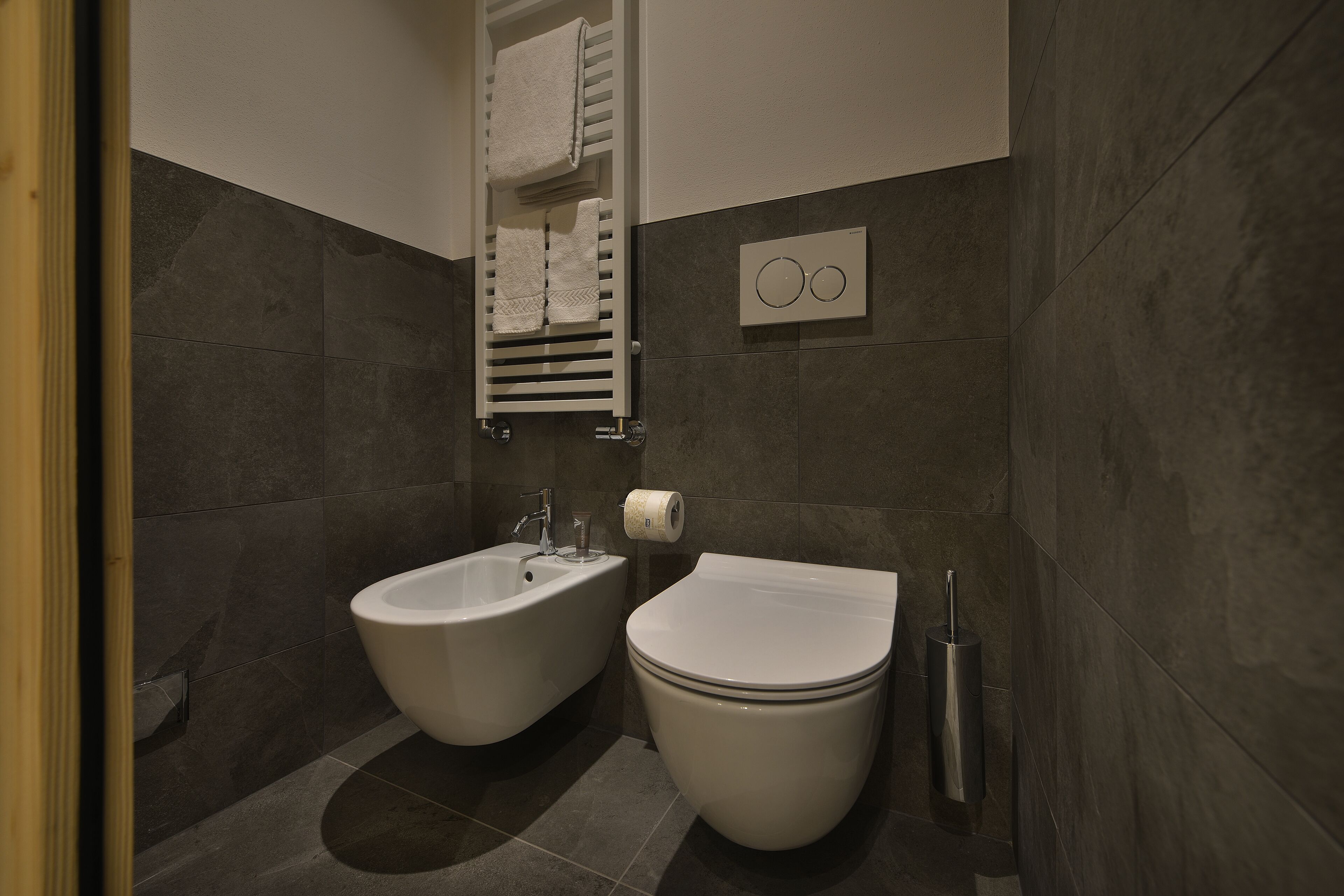 A modern bathroom with two sinks, a toilet, and a towel rack.