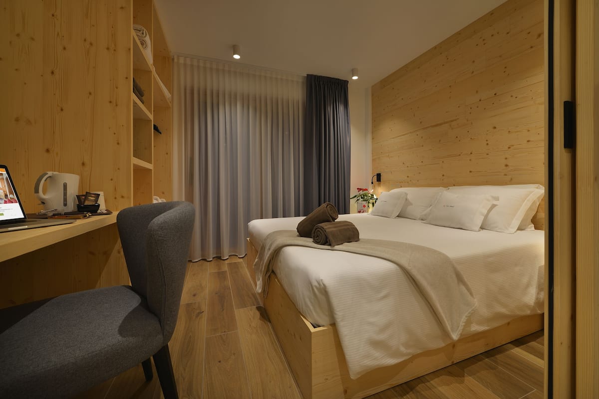 A modern hotel room with a wooden desk, a single bed, and a chair.