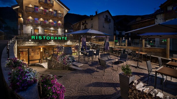 A restaurant with outdoor seating, a stone facade, and a sign that reads "RISTORANTE". - Hotel Valtellina (Livigno)