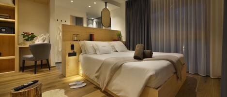 Una habitación de hotel moderna con una cama de madera, un escritorio pequeño, una silla y un ventanal con cortinas.