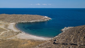 A coastal landscape with a rocky beach, clear blue waters, and a small white building near the shore. - Eneos Kythnos Beach Villas (Kithnos)