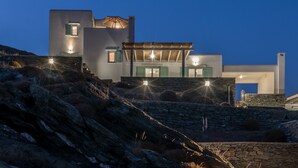 A modern building with multiple levels, stone walls, and a flat roof. - Eneos Kythnos Beach Villas (Kithnos)