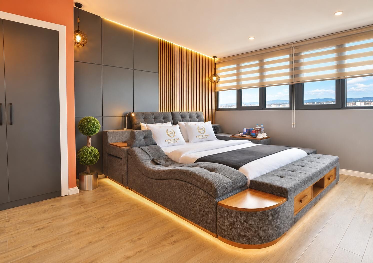 Un dormitorio moderno con una cama grande, almacenamiento integrado, una mesita de noche, una planta en maceta y vistas a la ciudad desde la ventana.