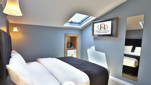 A modern hotel room with a skylight, a bed with white and black bedding, a bedside table with a lamp, and a mirror on the wall. - Sweet Home Suite Hotel (Trabzon)